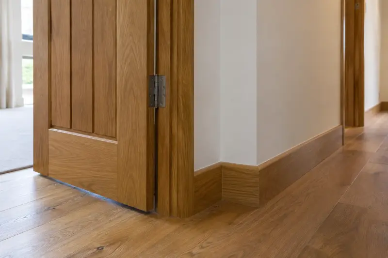 Illustrative detail of an open wooden door and an adjoining hallway corner.