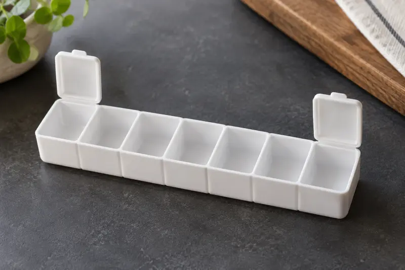 Empty white compartment tray with two end lids raised